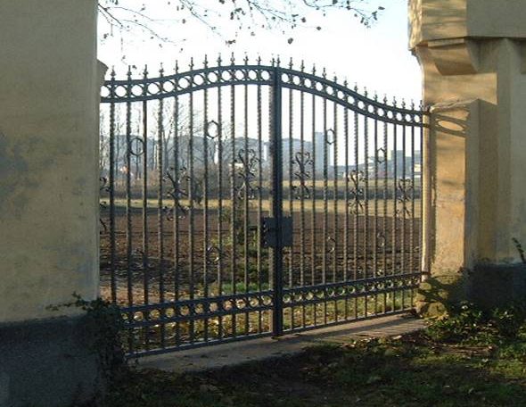 Ein großes, schmiedeeisernes Tor, das einen offenen Außenbereich absichert.